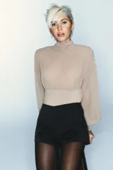 Body de cuello subido con mangas largas abullonadas y puños elásticos. Presenta un diseño combinado con paneles de tela semitransparente en la parte superior y cierre inferior con botones a presión.