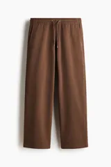 Pantalón deportivo de felpa marrón con elástico en la cintura, cordón de ajuste y bolsillos laterales, corte holgado.