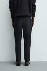 Pantalón de vestir regular fit color negro, confeccionado en tejido con mezcla de lana y elasticidad. Cuenta con cintura elástica, bolsillos frontales, bolsillos traseros de vivo con botón, y cierre frontal con cremallera y botón.