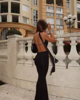 Vestido largo negro con escote halter, choker y abertura en el abdomen.