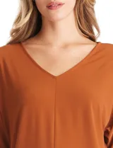 Blusa de silueta fluida con escote en V, manga japonesa corta y costura central vertical en el frente. Confeccionada en tejido de punto con acabado mate, presenta un diseño con largo asimétrico, siendo más larga en la espalda.