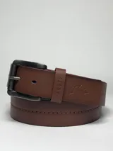 Cinturón de hombre color marrón con hebilla metálica envejecida. Presenta el logo de la marca grabado en el pasador y en la correa, con costuras decorativas en los bordes.