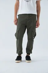 Pantalón cargo color beige, corte slim, con bolsillos laterales con botón, cierre con botón y puños en los tobillos.