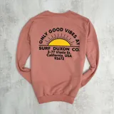 Buzo color salmón de algodón con cuello redondo, puños y cintura acanalados. Estampado en el frente con un sol y el texto "Only Good Vibes Surf Duxon Co. 3-77 Vissla St. California, USA 92672".