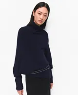 Jersey de punto azul marino, con cuello alto vuelto, de manga larga y diseño holgado.