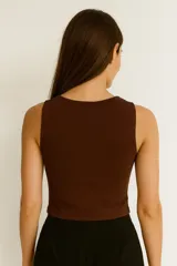 Top sin mangas color blanco hueso, de tejido acanalado, corte ajustado al cuerpo y cuello redondo con tres recortes en forma de ojo de cerradura en el centro del pecho.