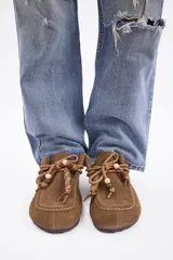 Zueco de cuero vacuno color marrón, con diseño de puntera reforzada y cordones decorativos con cuentas de madera en el empeine.