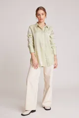Camisa verde claro de corte recto y mangas largas con puños abotonados. Cierre frontal con botones.