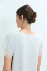 Camisón corto de color gris claro, con escote en V y mangas cortas, decorado con delicados detalles de encaje en el cuello y los bordes de las mangas.