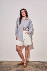 Camisa de corte oversize con diseño de rayas verticales en tonos azul y blanco. Presenta cuello clásico, cierre frontal con botones y mangas largas con puños abotonados.