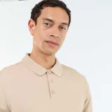 Remera polo de piqué de algodón en color beige, con cuello clásico y cierre frontal de tres botones.