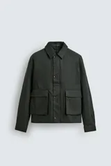 Cazadora relaxed fit color verde oscuro, confeccionada en tejido de algodón. Cuenta con cuello solapa, manga larga con puño abotonado, bolsillos plastrón con solapa en la cadera y cierre frontal de botonadura.