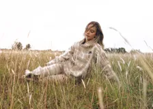 Sweater oversize de lana natural con estampado cuadrillé en tonos azul, verde y rojo. Presenta cuello alto, mangas largas y detalles de flecos torneados en el cuello, puños y dobladillo.