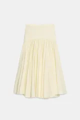 Falda de tiro medio color amarillo claro, confeccionada en tejido de punto elástico con detalle de aplicación combinada y bajo en línea evasé. Cuenta con cierre lateral con cremallera oculta.