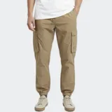 Pantalón cargo de nylon color beige, con elástico en la cintura y en los puños. Presenta bolsillos laterales tipo cargo con solapa y un logo de goma aplicado en uno de ellos.