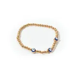 Pulsera elástica de mostacillas doradas con dijes de ojo turco azul y blanco.