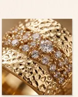 Anillo ancho de bronce con baño de oro, diseño texturizado en relieve y detalles de circonias engarzadas.