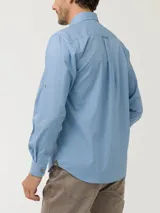 Camisa celeste de manga larga RKF Galiton, confeccionada en popelina 100% algodón orgánico. Cuenta con botones de madera, mangas ajustables, bolsillo de pecho con logo bordado y protección UPF +20.
