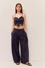 Blusa crop azul marino con tirantes finos y detalle de nudo frontal con forma de flor, con tiras para atar en la cintura.