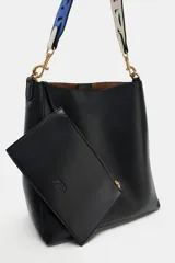 Bolso de hombro formato saca de color negro, con cierre mediante clip metálico y un compartimento interior extraíble con cremallera. Incluye un asa de hombro con diseño estampado y detalles metálicos dorados.