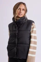 Chaleco de abrigo tipo puffer en color negro, con cuello alto, cierre frontal con cremallera y botones a presión.