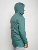 Parka larga gris con capucha, cierre frontal con cremallera y botones a presión, múltiples bolsillos y logo de Umbro en el pecho.