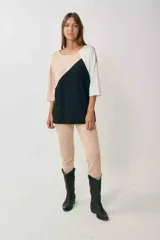 Remerón de manga tres cuartos con diseño tricolor en bloques diagonales: negro en el centro, beige claro en la parte superior izquierda y blanco en la manga derecha.