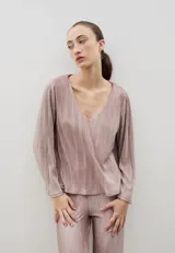 Blusa plisada de color crema con escote en V y mangas largas ligeramente acampanadas. Presenta una textura plisada en toda la prenda que aporta caída y movimiento.