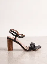 Sandalia de cuero negro, con tira delantera ancha, doble tira ajustable en el talón con hebilla metálica y taco ancho símil madera.