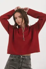 Sweater de punto color rojo con cuello polo, cierre frontal parcial con botones y detalle de costura en contraste a lo largo de la tapeta.