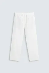 Pantalón blanco de corte relajado (relaxed fit) con cintura elástica ajustable mediante cordón. Presenta bolsillos frontales y bolsillos traseros de vivo.