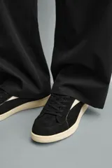 Zapatilla de estilo retro con cordones, confeccionada en una combinación de piezas de gamuza y material sintético. Presenta suela de goma a contraste y diseño de paneles laterales.