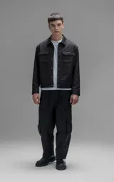 Chaqueta de corte regular crop confeccionada en microfibra pesada levemente elastizada. Presenta un diseño inspirado en la campera de jean clásica, con cuello volcado, cierre frontal mediante broches snap a tono y dos bolsillos delanteros con solapa.