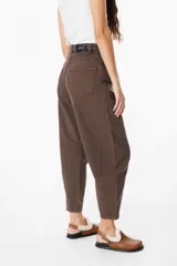 Jean de corte balloon en color azul marino, con cintura alta, cierre frontal con botón y bolsillos laterales. Presenta costuras laterales curvadas que definen su silueta amplia y relajada.