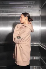 Buzo oversize color nude confeccionado en frisa, con capucha amplia, bolsillo canguro, terminaciones de puño y ruedo con rib, y logo de la marca bordado en el centro delantero.