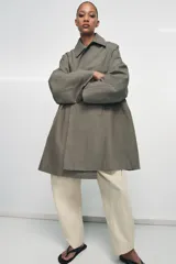 Trench oversize de Zara Woman Collection, confeccionado en hilatura de algodón. Presenta cuello solapa, manga larga, bolsillos delanteros y cierre frontal con botones ocultos bajo solapa.