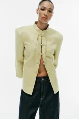 Blazer de jacquard color amarillo claro, con cuello mao, mangas 3/4 y cierre frontal con alamares. Presenta diseño estampado de inspiración oriental.
