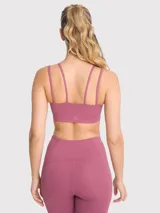 Top deportivo color rosa viejo con tirantes finos y detalle de tiras cruzadas en el frente. Cuenta con soporte medio y almohadillas removibles.