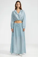 Falda larga hasta el tobillo color celeste, confeccionada en tejido arrugado liviano con cintura elástica.