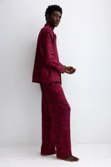 Pijama de dos piezas confeccionado en franela de algodón. Incluye una camisa de manga larga con cuello inglés, botones frontales y bolsillo en el pecho, junto con un pantalón de corte recto con cintura elástica y cordón ajustable.