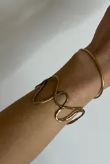 Brazalete rígido plateado con diseño irregular de ondas.