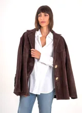 Blazer marrón chocolate de gamuza con forro interno, corte holgado, cuello clásico, cierre frontal con botones dorados, bolsillos laterales y detalle de flecos en las mangas. 