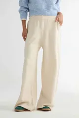 Pantalón de tejido de punto en color crudo, de corte amplio y tiro alto con cintura elástica. Presenta bolsillos frontales tipo parche y diseño de pierna recta y holgada.