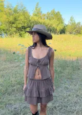 Falda corta color chocolate con diseño de volados escalonados y short incorporado. Presenta una silueta liviana y fluida con cintura elástica.