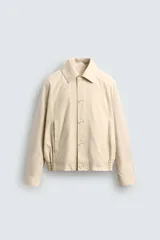 Cazadora boxy fit color beige, confeccionada en tejido de algodón y lino. Presenta cuello solapa, manga larga con puño abotonado, bolsillos de vivo en la cadera y bajo con elásticos laterales. Cierre frontal de botonadura.