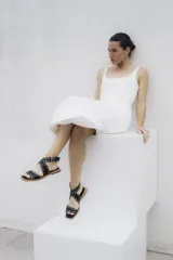 Sandalias bajas de cuero negro con tachas plateadas, tiras cruzadas y hebilla al tobillo.