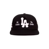 Gorro trucker negro con diseño bordado en color blanco que incluye las letras "LA" al centro y la frase "Mi Casa Su Casa" a los lados.
