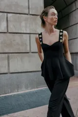 Top negro de tejido elástico, corte peplum, escote corazón y tirantes anchos decorados con aplicaciones de joyas doradas en forma de flor.