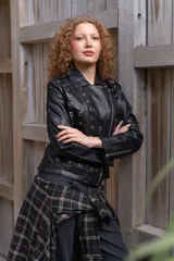 Campera de eco cuero negro con solapas anchas, cierre diagonal metálico y detalle de múltiples ojalillos metálicos distribuidos en el frente y las mangas.