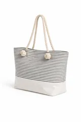 Bolso de tela tipo tote bag con estampado de rayas horizontales azules y blancas, y base de color beige. Tiene asas de cuerda de color beige.